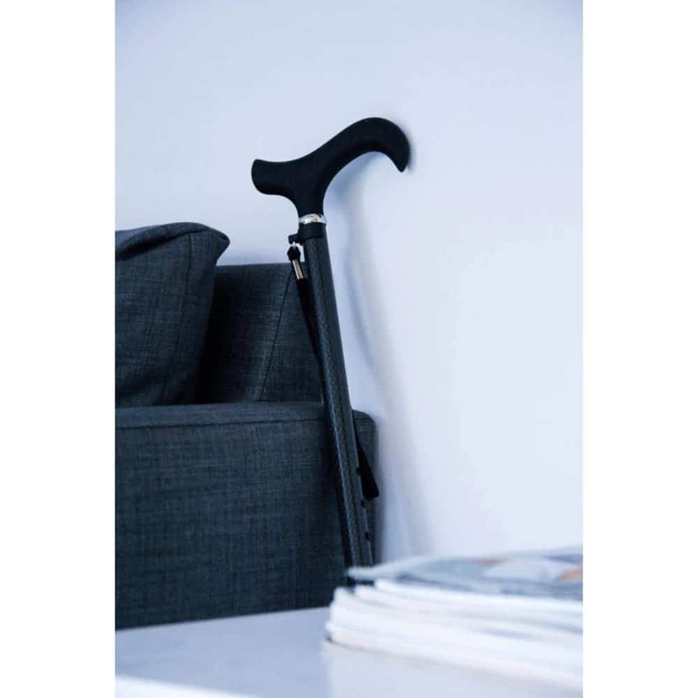 Käpp i kolfiber placerad bredvid soffa