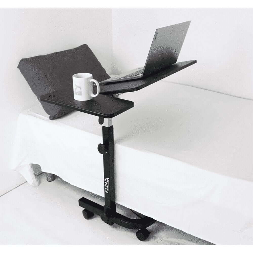 Multifunktionellt bord på hjul placerat vid säng med laptop och kaffekopp.
