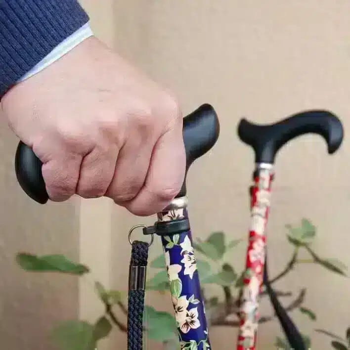 Hopfällbar käpp med blommönster Hand håller i hopfällbar promenadkäpp med blått blommönster