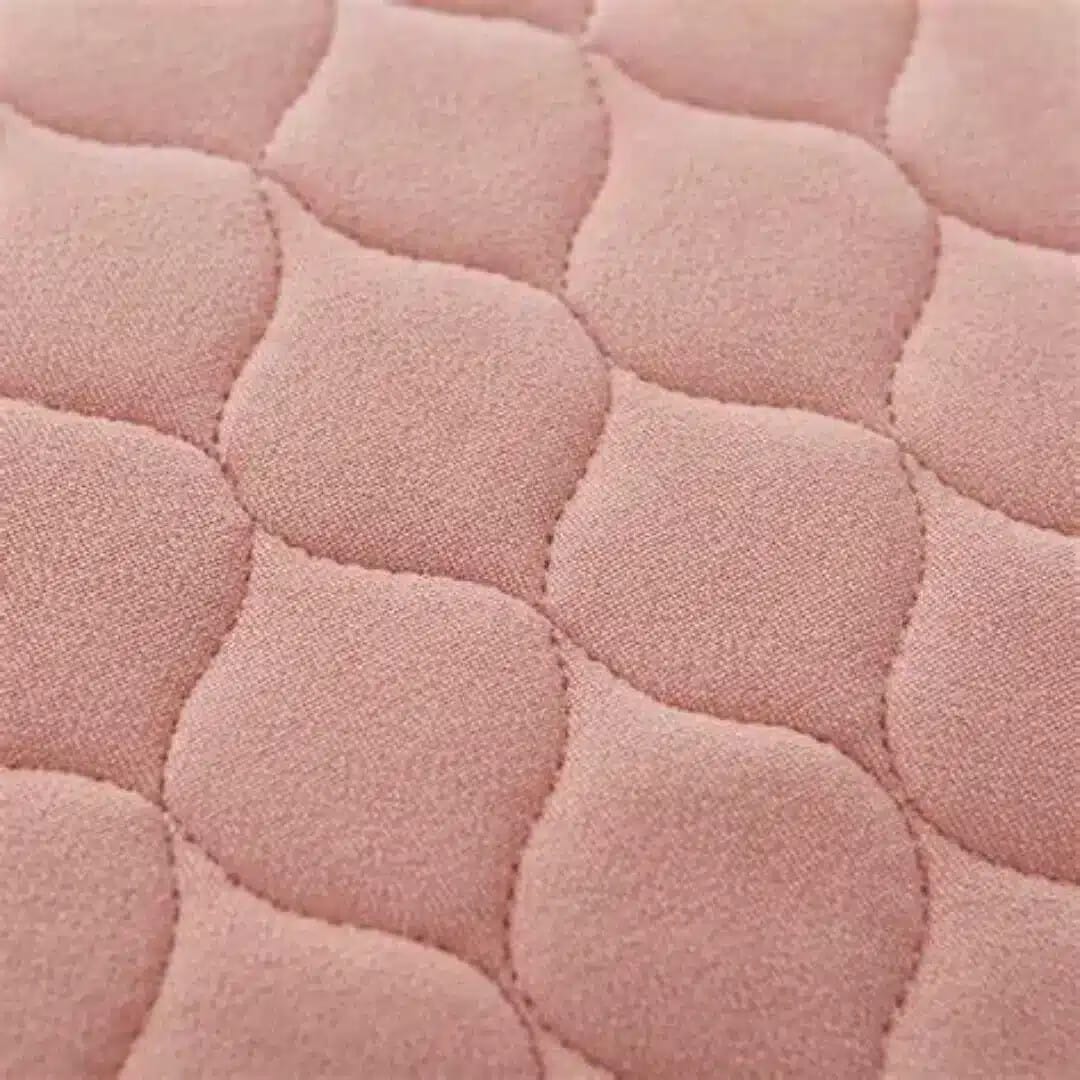 Inkontinensskydd för säng tvättbar i rosa färg, närbild på quiltad yta