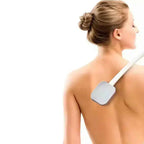 Applicator för ryggkräm. Kvinna använder en lotionapplicator med långt handtag för att applicera kräm på ryggen.