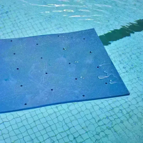 Vattenterapimatta för barn – detaljvy Blå vattenterapimatta för barn i stillastående pool – visar hålmönster och materialets yta.