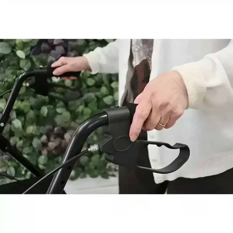 Handtag och broms på hopfällbar rollator Person som håller i handtagen på en svart hopfällbar rollator med bromsfunktion.