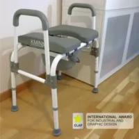 Toilet chair with armrests, soft seat and bucket underneath – placed on the floor in a home environment.