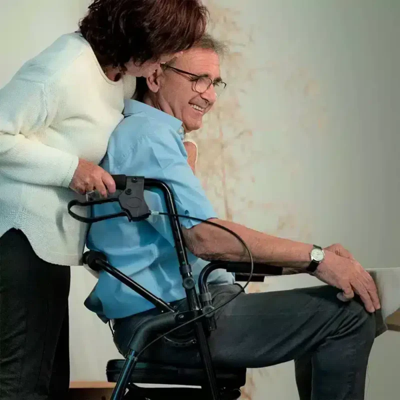 Rullator som även fungerar som transportstol En person sitter i rullator med rullstolsfunktion och blir skjutsad av en annan person