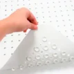Duschmatta 97 x 35 cm med sugkoppar i vit naturgummi lyfts upp för att visa halkskydd