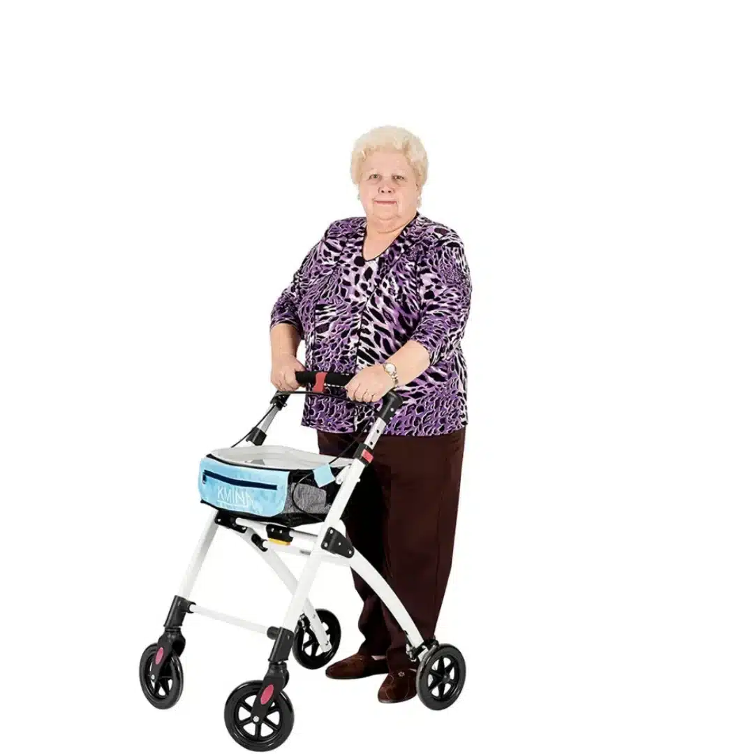 Äldre kvinna som går med smal vit rollator med blå korg på vit bakgrund.