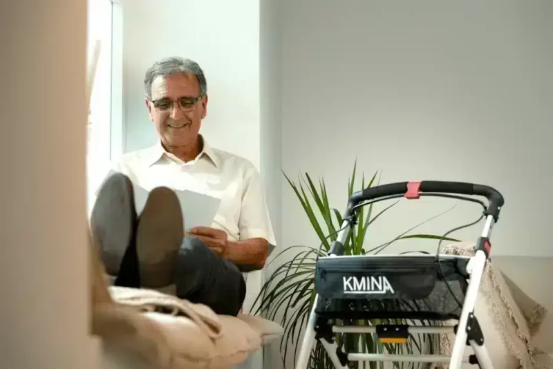 Rullator för trygg vila Man sitter och vilar bredvid sin hopfällbara rullator.