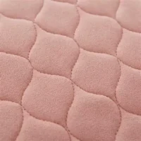 Incontinence cover for bed washable in pink color, close-up of quilted surface