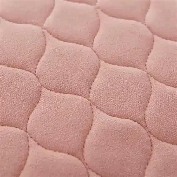 Inkontinensskydd för säng tvättbar i rosa färg, närbild på quiltad yta