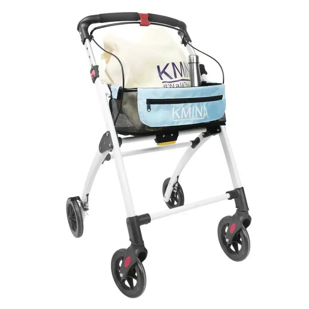 Vit smal rollator med blå korg och textilpåse placerad ovanpå sitsen.