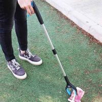 Person picks up trash with foldable tongs with magnet and rotating claw