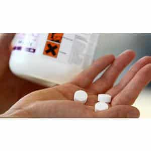 a hand holding pills and a bottle