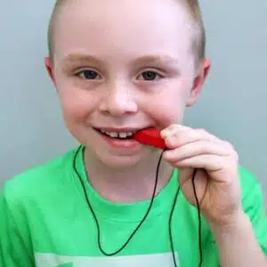 a boy with a necklace in his mouth