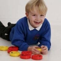a boy lying on the floor playing with colorful plastic discs