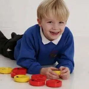 a boy lying on the floor playing with colorful plastic discs