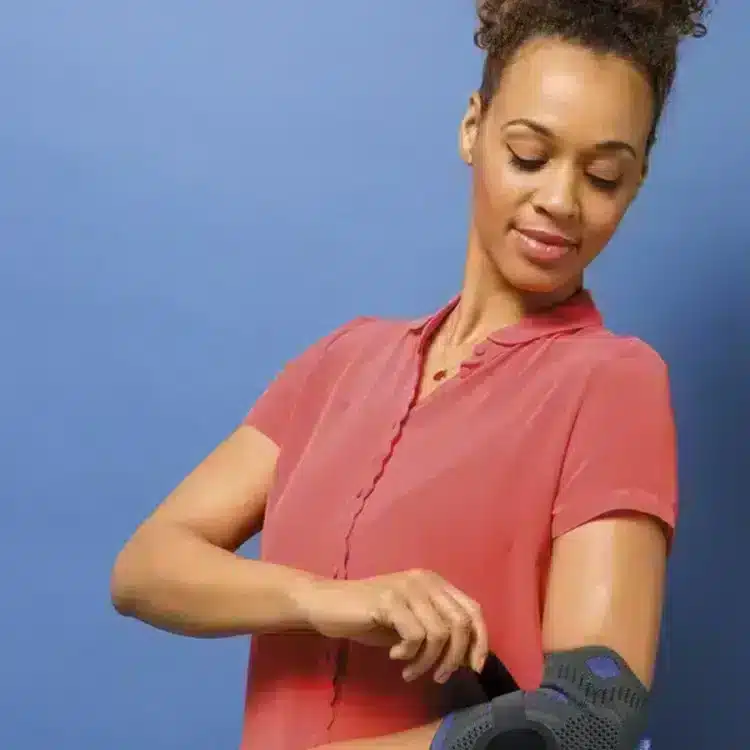 Silistab Epi armbågsortos 5.Kvinna som justerar sitt Silistab Epi armbågsstöd för perfekt passform.