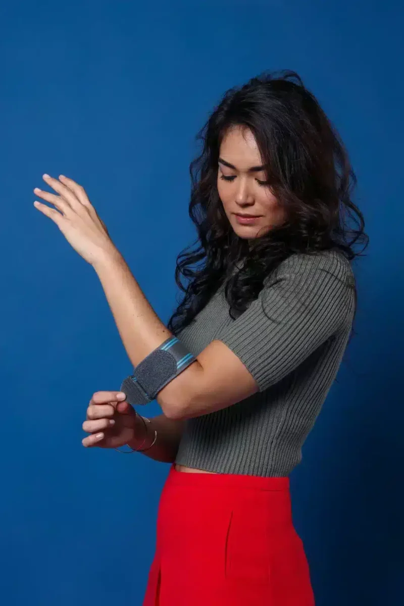 Kvinna bär ortos för tennisarmbåge i stående position
