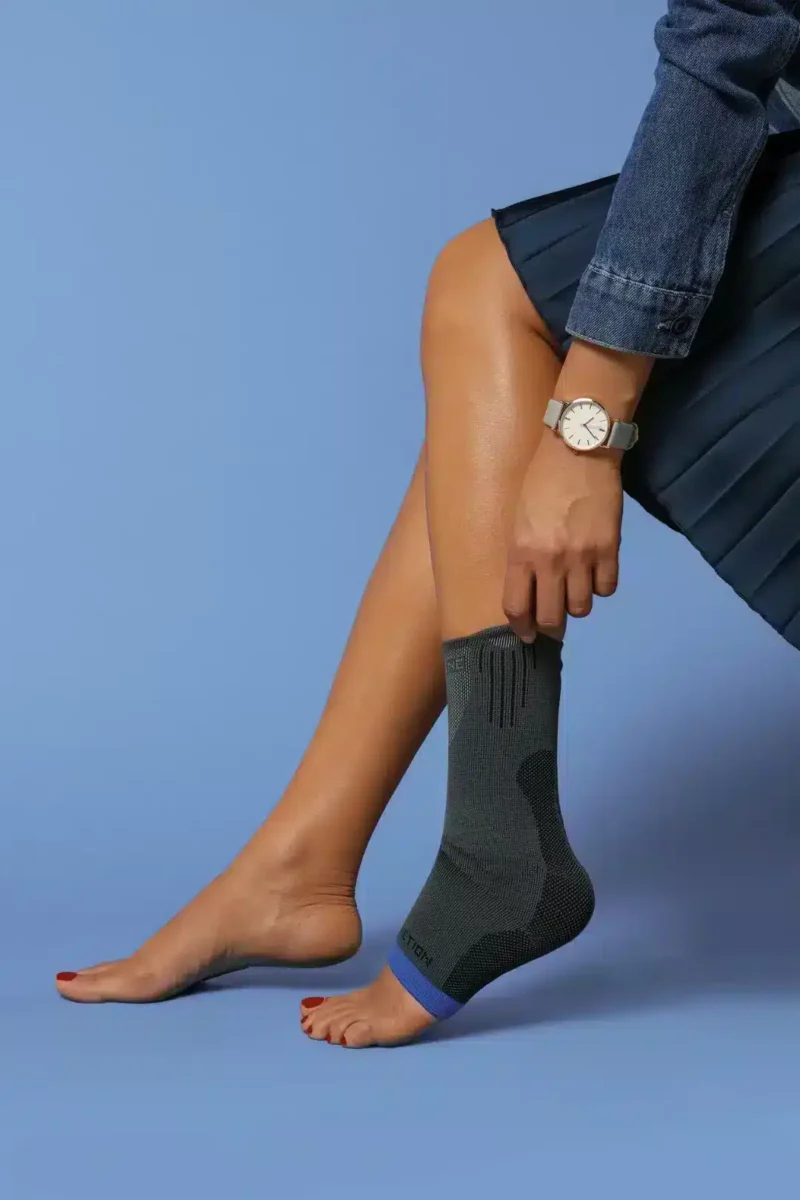 Malleo Action ankelstöd – kompression för fotled Elastiskt ankelstöd Malleo Action – visas på ben i sittande position mot blå bakgrund