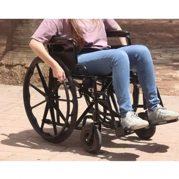 Person uses folding manual wheelchair, seat size 43 cm, outdoors.