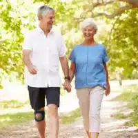 Person walking outdoors on a path, wearing knee pads with open kneecaps.